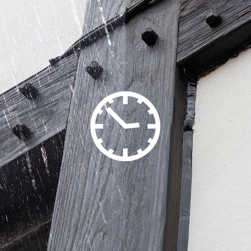an image of the side of a house using tudor board with a clock icon on it. Half of the image displays rainfall on the tudor board.